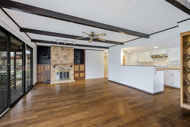 unfurnished living room featuring beamed ceiling, a ceiling fan, dark wood-style floors, and a fireplace