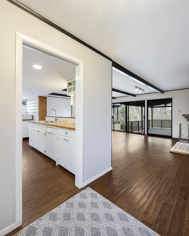 hall featuring a sink, baseboards, dark wood-type flooring, and beam ceiling