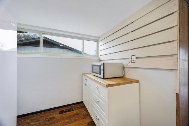 interior space with stainless steel microwave, baseboards, visible vents, and wood finished floors