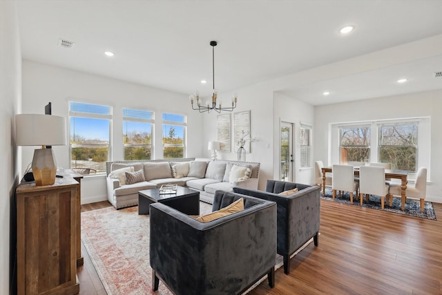 living room with visible vents, wood finished floors, recessed lighting, an inviting chandelier, and baseboards