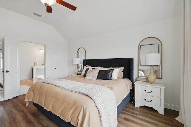 bedroom featuring visible vents, lofted ceiling, ensuite bathroom, wood finished floors, and a ceiling fan