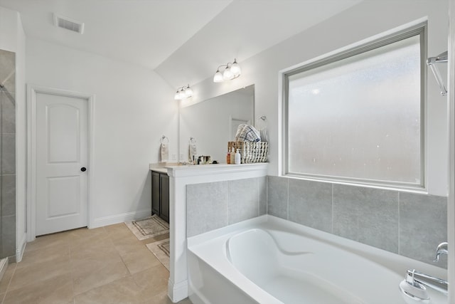 bathroom with visible vents, a garden tub, vaulted ceiling, tile patterned floors, and vanity