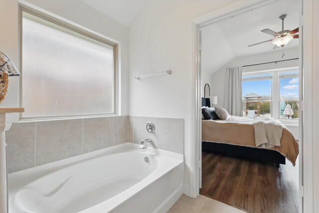 bathroom featuring a ceiling fan, wood finished floors, connected bathroom, a bath, and vaulted ceiling