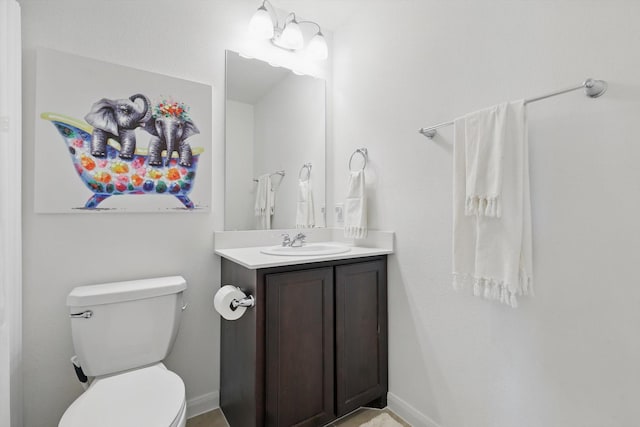 bathroom with vanity, toilet, and baseboards