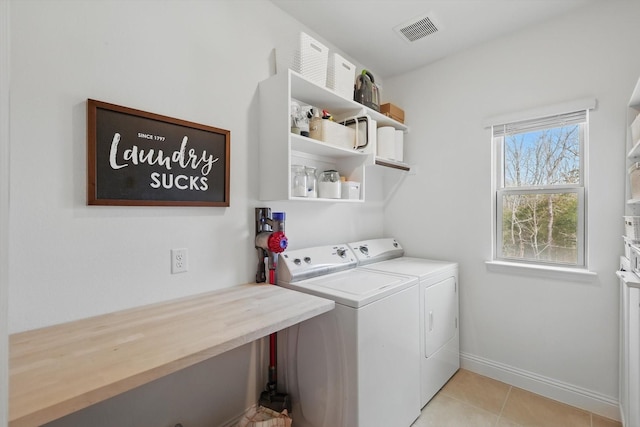 washroom featuring light tile patterned floors, baseboards, visible vents, washing machine and clothes dryer, and laundry area