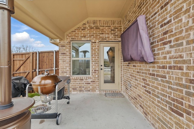 property entrance featuring a patio, fence, and brick siding