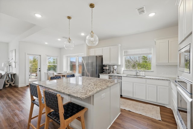 kitchen featuring dark wood-type flooring, visible vents, appliances with stainless steel finishes, and a sink