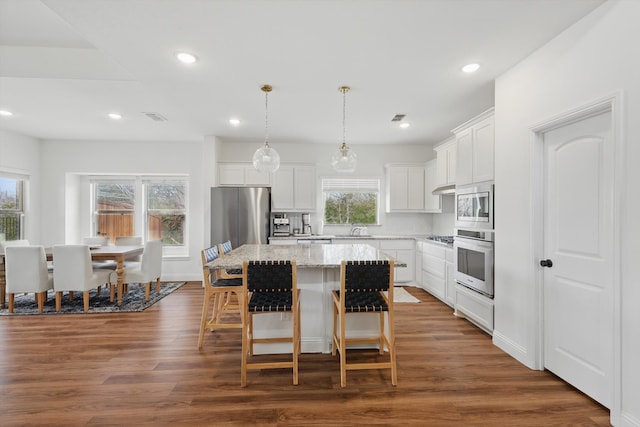 kitchen featuring dark wood-type flooring, a center island, under cabinet range hood, and stainless steel appliances