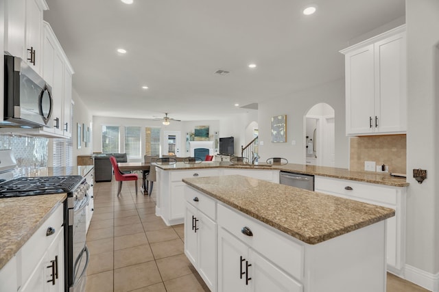 kitchen with a ceiling fan, visible vents, arched walkways, stainless steel appliances, and open floor plan