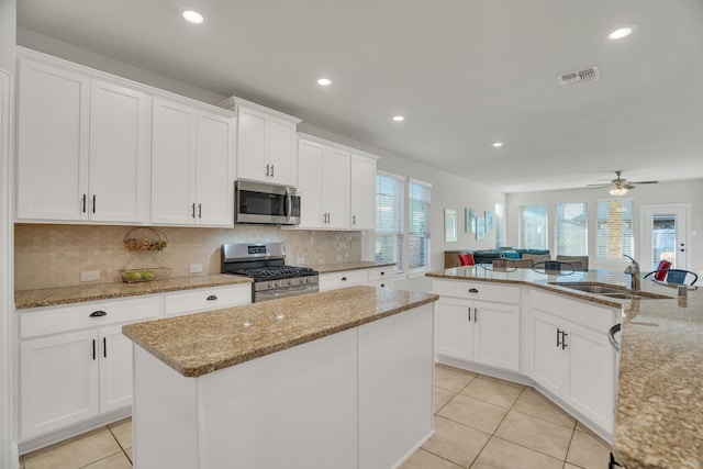 kitchen with light tile patterned floors, visible vents, a sink, appliances with stainless steel finishes, and a center island