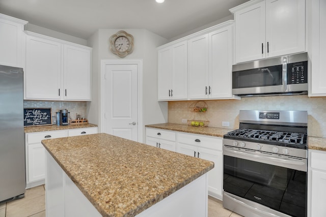 kitchen with stainless steel appliances, tasteful backsplash, a kitchen island, and white cabinets