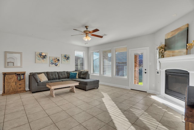 living area with a ceiling fan, visible vents, baseboards, light tile patterned flooring, and a glass covered fireplace