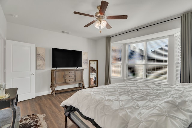 bedroom featuring ceiling fan, visible vents, baseboards, and wood finished floors