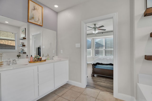 bathroom featuring a sink, connected bathroom, baseboards, and tile patterned flooring