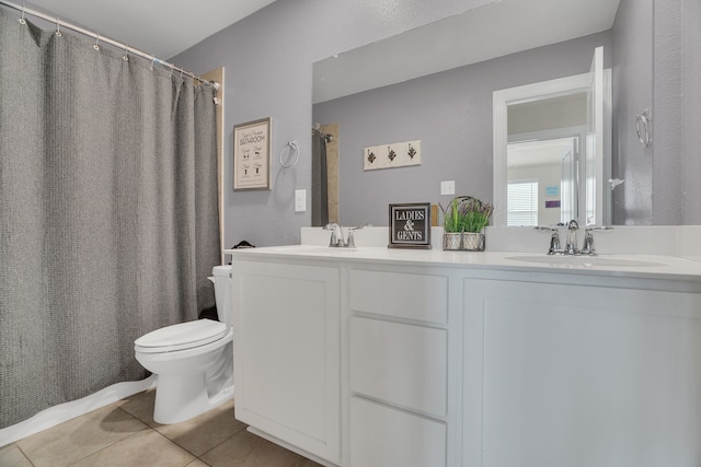 bathroom with tile patterned floors, double vanity, toilet, and a sink