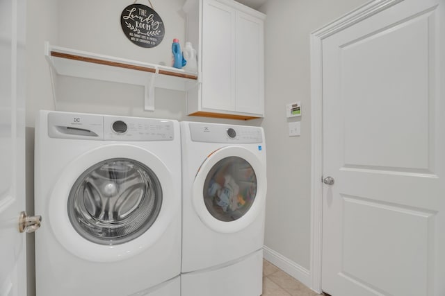 laundry room with washing machine and clothes dryer, light tile patterned floors, cabinet space, and baseboards