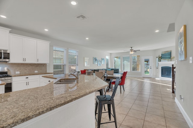 kitchen with visible vents, backsplash, open floor plan, appliances with stainless steel finishes, and a sink