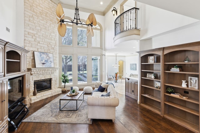 living area with dark wood-style floors, visible vents, a towering ceiling, and a chandelier