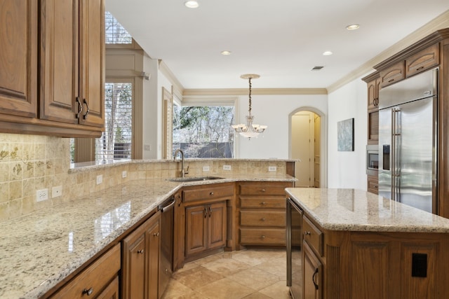 kitchen with a peninsula, arched walkways, a sink, built in appliances, and tasteful backsplash