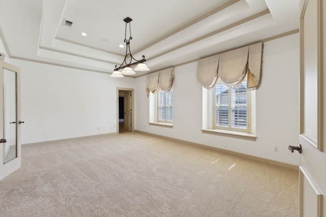 carpeted empty room with a raised ceiling, visible vents, baseboards, and ornamental molding