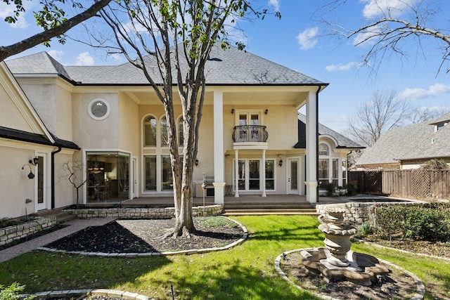 rear view of house with a balcony, fence, stucco siding, french doors, and a patio area