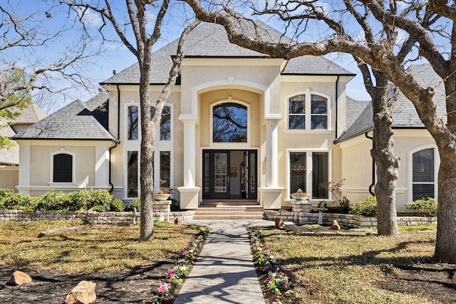 french country style house with stucco siding and a shingled roof