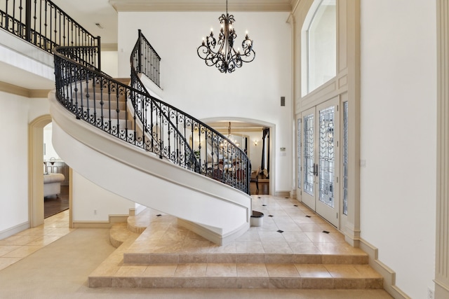 entrance foyer with arched walkways, stairway, a notable chandelier, and ornamental molding