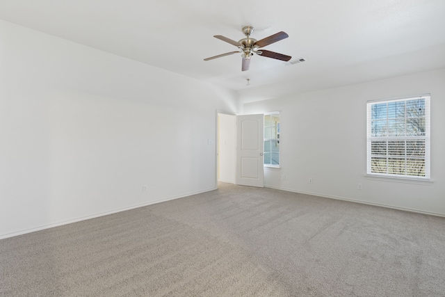 empty room with a ceiling fan, light colored carpet, visible vents, and baseboards