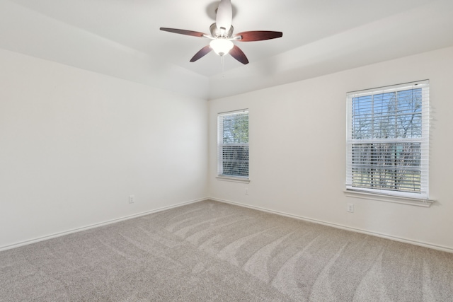 carpeted spare room featuring ceiling fan and baseboards