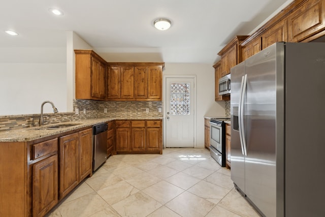 kitchen with backsplash, brown cabinets, appliances with stainless steel finishes, and a sink