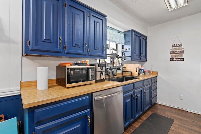 kitchen featuring a sink, stainless steel appliances, dark wood-type flooring, a textured ceiling, and blue cabinets