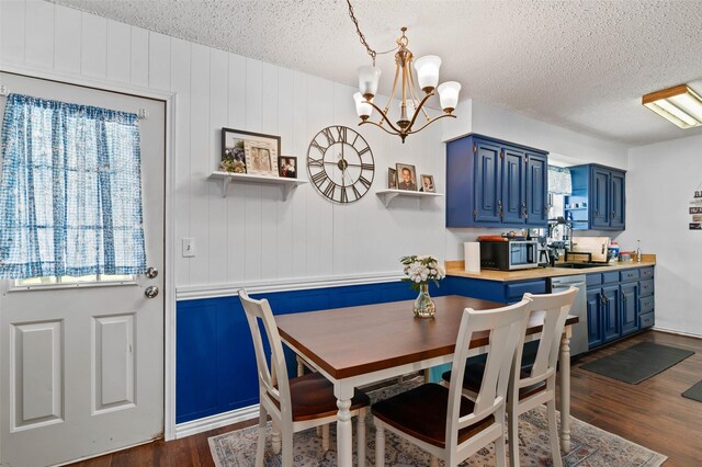 dining area featuring dark wood finished floors, an inviting chandelier, and a textured ceiling