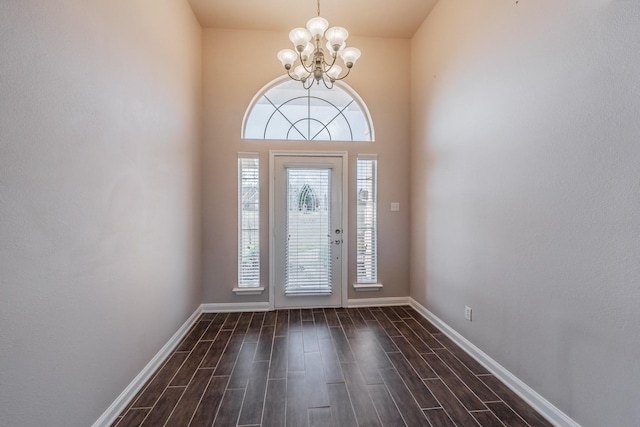 entrance foyer with baseboards, an inviting chandelier, and wood tiled floor