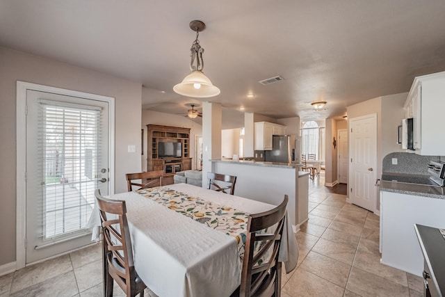 dining area featuring light tile patterned floors, a ceiling fan, visible vents, and a wealth of natural light