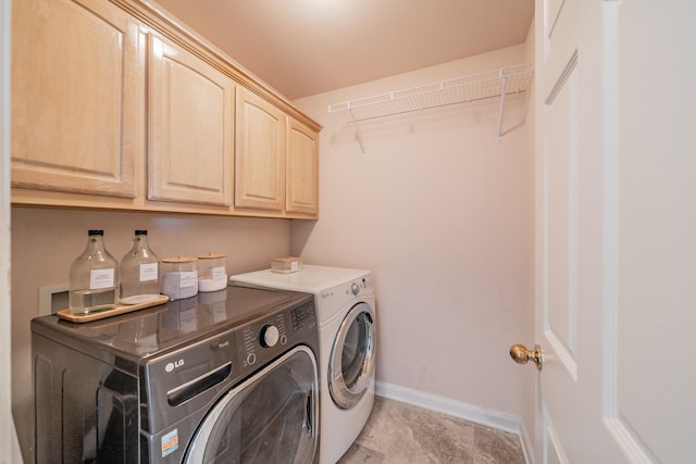 washroom featuring washing machine and dryer, cabinet space, and baseboards