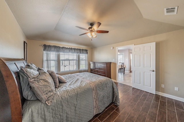 bedroom featuring visible vents, ceiling fan, baseboards, wood finish floors, and lofted ceiling