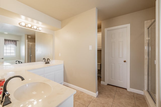 bathroom featuring baseboards, double vanity, a stall shower, a sink, and tile patterned flooring