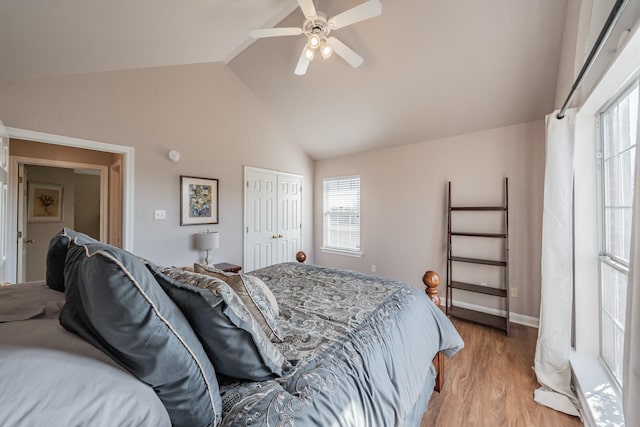 bedroom featuring light wood-style flooring, a ceiling fan, a closet, baseboards, and lofted ceiling