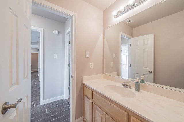 bathroom with vanity, baseboards, visible vents, and wood finish floors