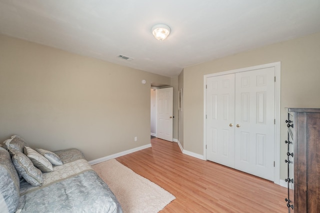 bedroom with visible vents, baseboards, a closet, and light wood finished floors