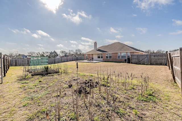 view of yard featuring a patio, a vegetable garden, and a fenced backyard