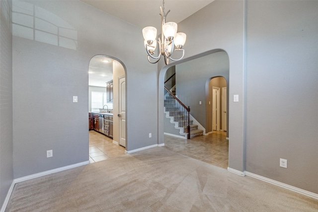 unfurnished room with stairway, light colored carpet, light tile patterned floors, arched walkways, and a sink