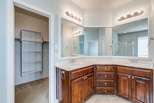 full bath featuring double vanity, a shower stall, tile patterned floors, and a sink