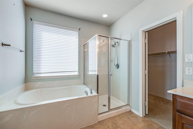 full bath featuring vanity, a shower stall, a walk in closet, tile patterned floors, and a bath