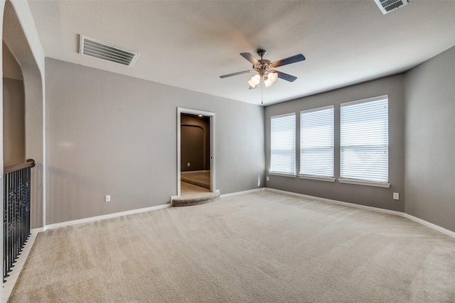 empty room with visible vents, light carpet, baseboards, and a ceiling fan