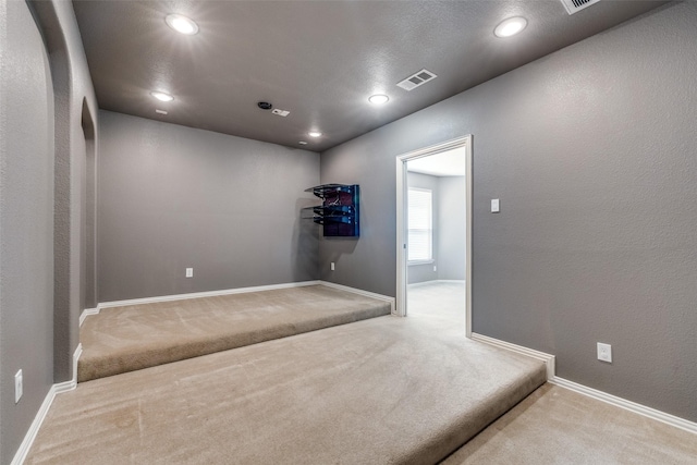 interior space featuring carpet, visible vents, baseboards, recessed lighting, and a textured wall