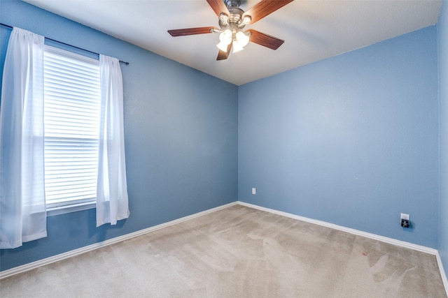 carpeted spare room with ceiling fan and baseboards