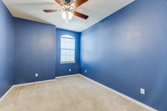 carpeted spare room featuring baseboards, ceiling fan, and a textured wall