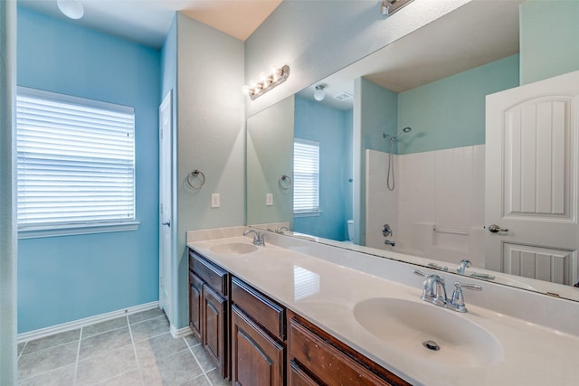 bathroom with a sink, baseboards, double vanity, and tile patterned floors