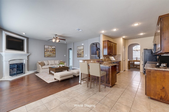 kitchen with arched walkways, light tile patterned floors, and a kitchen breakfast bar